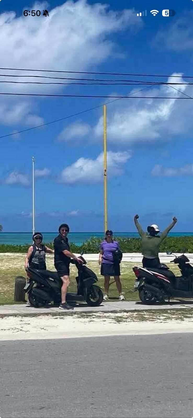 Guests pausing with scooters during a sunny San Salvador island outing